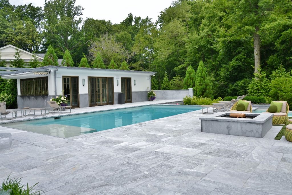 Terrassenplatten aus Stein mit Grill und Poolrand aus Steinplatten in grau