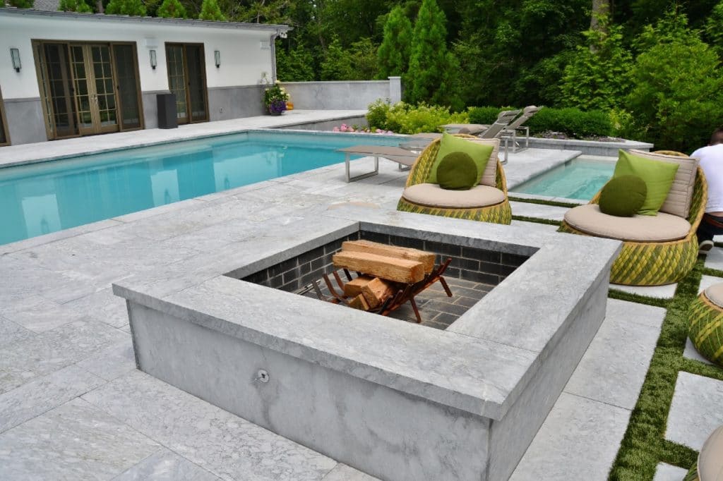 Terrassenplatten aus Stein mit Grill und Poolrand aus Steinplatten in grau