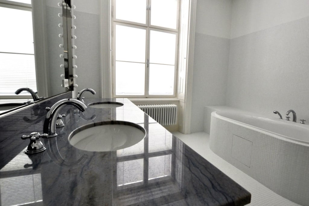 Polished quartzite washbasin in dark grey with bath and wall tiles in white